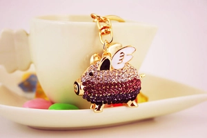 Macro shot of pink rhinestone flying pig keychain with gold wings and crystal details