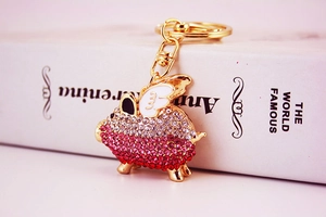 Detailed view of a crystal-encrusted pig keychain with wings and a golden ring hook