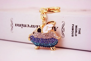 Detailed macro of gold flying pig keychain with blue rhinestones on a vintage book