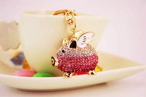 Close-up of a golden pig keychain featuring pink and red gradient rhinestones on wings