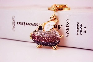 Macro shot of gradient crystal encrusted flying pig keychain with gold-plated details