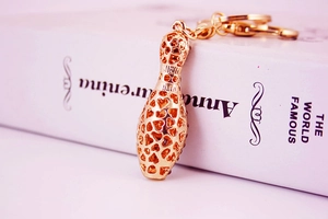 Close-up of golden hollowed-out bowling pin keychain on a book with blurred background
