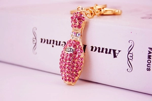 Close-up of pink crystal bowling pin keychain with gold LUCKY engraving and metal loop