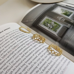 Macro shot of three textured gold-finished alloy rings on minimalist book pages
