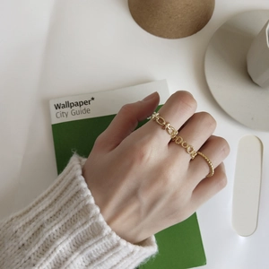 Detail of gold twisted rope and chain link rings worn together in a minimal style