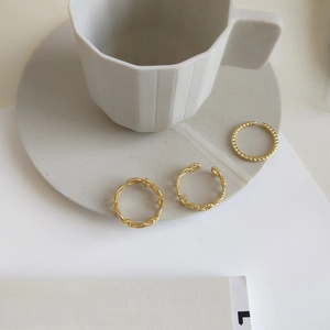 Detailed macro shot of three gold minimalist textured rings on a grey ceramic tray