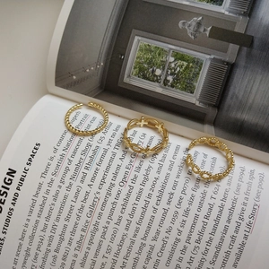 Detailed view of three gold adjustable rings with twisted and chain textures on a book