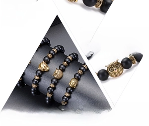 Detail of 8mm matte black stone bracelets with golden leopard, owl, and Buddha charms