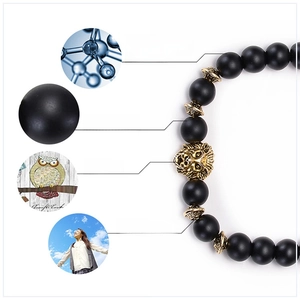 Detail of black matte 8mm beaded bracelet with golden lion head and stress relief icons