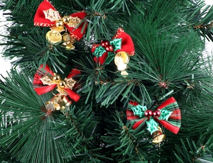 Close-up of red velvet bows with golden bells on Christmas tree branches