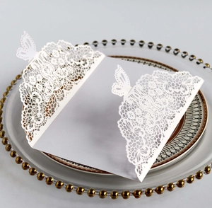 Macro detail of laser-cut butterfly lace patterns on elegant white wedding invitation card