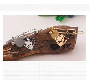 Detail of mother-child heart charm bracelet in gold and silver finish on wood