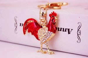 Close-up of a red rooster keychain with gold finish and sparkling rhinestones