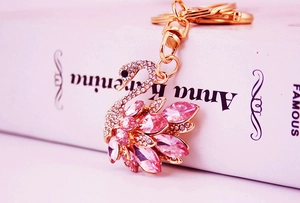 Detail view of a golden swan keychain with pink crystals on an Anna Karenina book