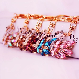 Set of five gold swan keychains with colorful crystals on a book background