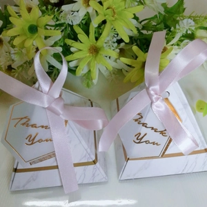 Detail of pyramid marble gift boxes with pink ribbons and gold Thank You lettering