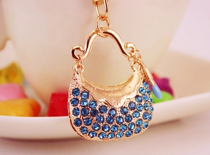 Detailed macro view of a golden handbag keychain with blue rhinestones and lipstick charm