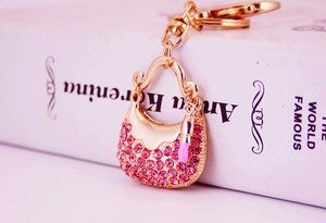 Close-up of golden handbag keychain with pink rhinestones and lipstick pendant