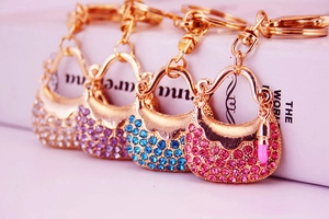 Macro detail of four gold-toned handbag keychains with pink, blue, and purple rhinestones