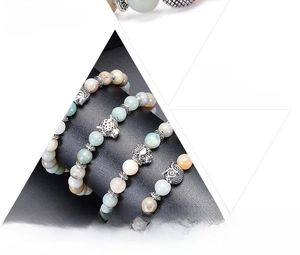 Detail of natural stone bracelets featuring silver Buddha, leopard, lion, and owl charms