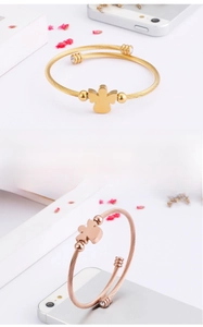 Close-up of gold and rose gold twisted bangles with angel-shaped charms and zircons