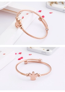 Detail of rose gold titanium bangle featuring twisted cable design and angel zircon charm