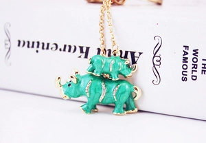 Detailed close-up of green and gold rhino pendants with crystal rhinestones on a metal chain