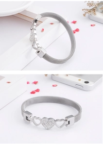 Detail of silver woven mesh bracelet with central zircon heart and hollow heart charms