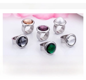 Detailed view of six stainless steel rings with colorful glass stones and shell pearl