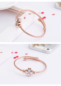 Detail view of rose gold clover bracelet with shell inlay and spiral twisted metal band