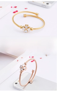 Detail of clover bracelet featuring white shell inlay and zircon accents on twisted band