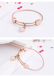 Detail of rose gold bracelet featuring heart charms and white heart-shaped pendant
