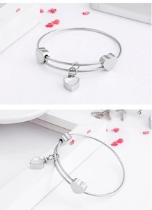Detailed macro view of silver steel wire bracelet featuring a functional heart locket charm