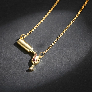 Golden necklace featuring a wine bottle pouring into a red heart zircon cup pendant