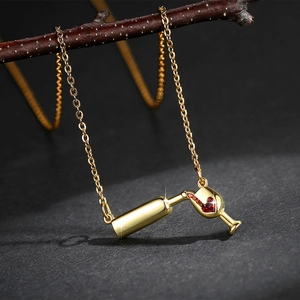 Detail of gold wine bottle and glass pendant necklace with red zircon liquid flow