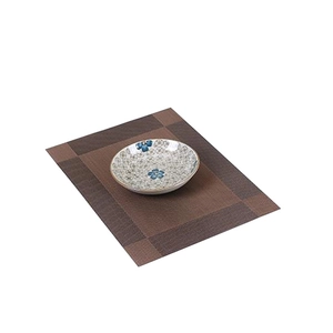 Brown woven Teslin placemat with rectangle texture and floral ceramic bowl on white background