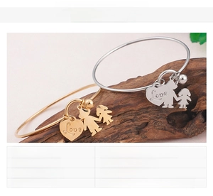 Détail de bracelets avec breloque cœur en or et argent sur support en bois