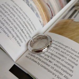 Macro shot of minimalist polished silver wide ring band on a book page surface