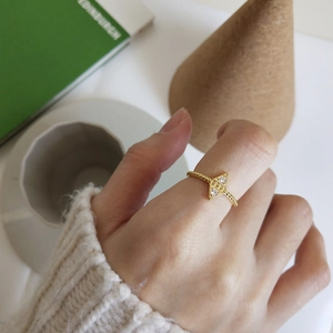 Detail of geometric gold ring with zircons and woven texture worn on finger