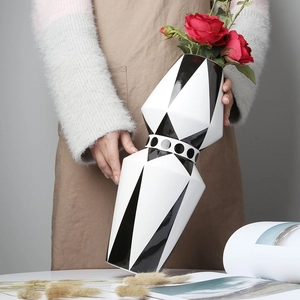 Detail einer handgehaltenen geometrischen Keramikvase mit schwarz-weißem Polka-Dot-Muster
