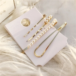 Elegant 4-piece set of gold geometric hair clips with faux pearls and rhinestones on card