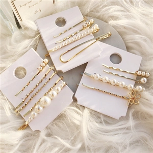 Close-up of elegant gold metal hair pins set with faux pearls on a white fur background