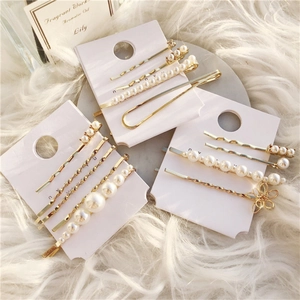 Elegant gold geometric pearl hair clip set for women displayed on a soft white plush background