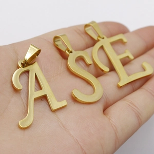 Gold stainless steel initial pendants A, S, E held in hand showing polished finish
