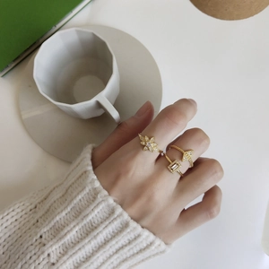 Three gold-plated 925 silver rings with zircon flower and geometric designs on model's hand