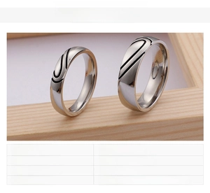 Detail of couple stainless steel heart rings with black streamlined groove design