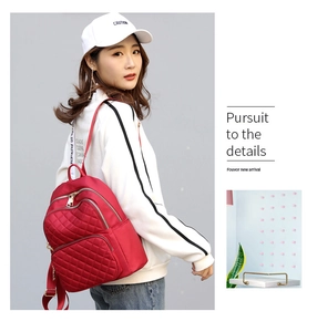 Detail of red quilted nylon backpack with gold zippers and layered storage pockets