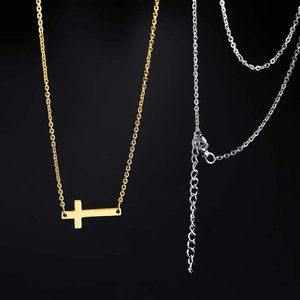 Détails du collier croix dorée et de la chaîne argentée avec fermoir mousqueton