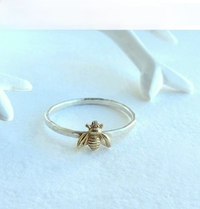 Detailed macro view of a 3D gold bee design on a polished silver band ring
