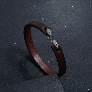 Detail view of dark brown leather bracelet with vintage silver metal clasp on black box
